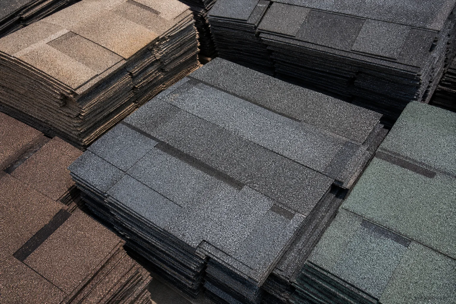 Close-up of asphalt shingle bundles with visible granules in a supply yard.